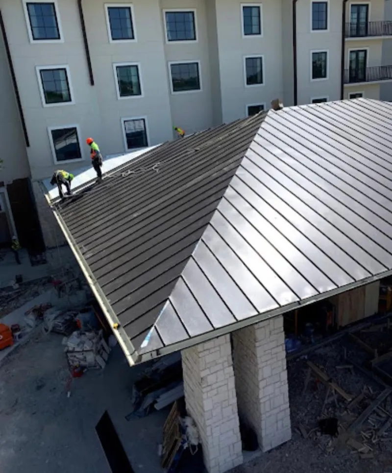 Crew installing standing seam metal roof panels on a commercial project in Hartland